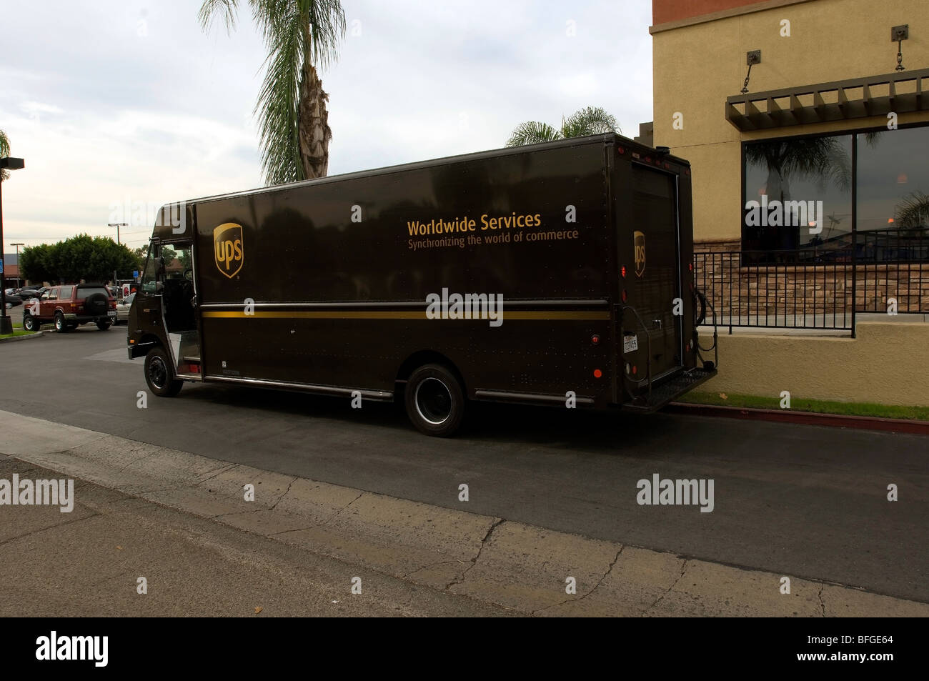 Brown UPS truck parked in front of a business making a rush delivery. Stock Photo