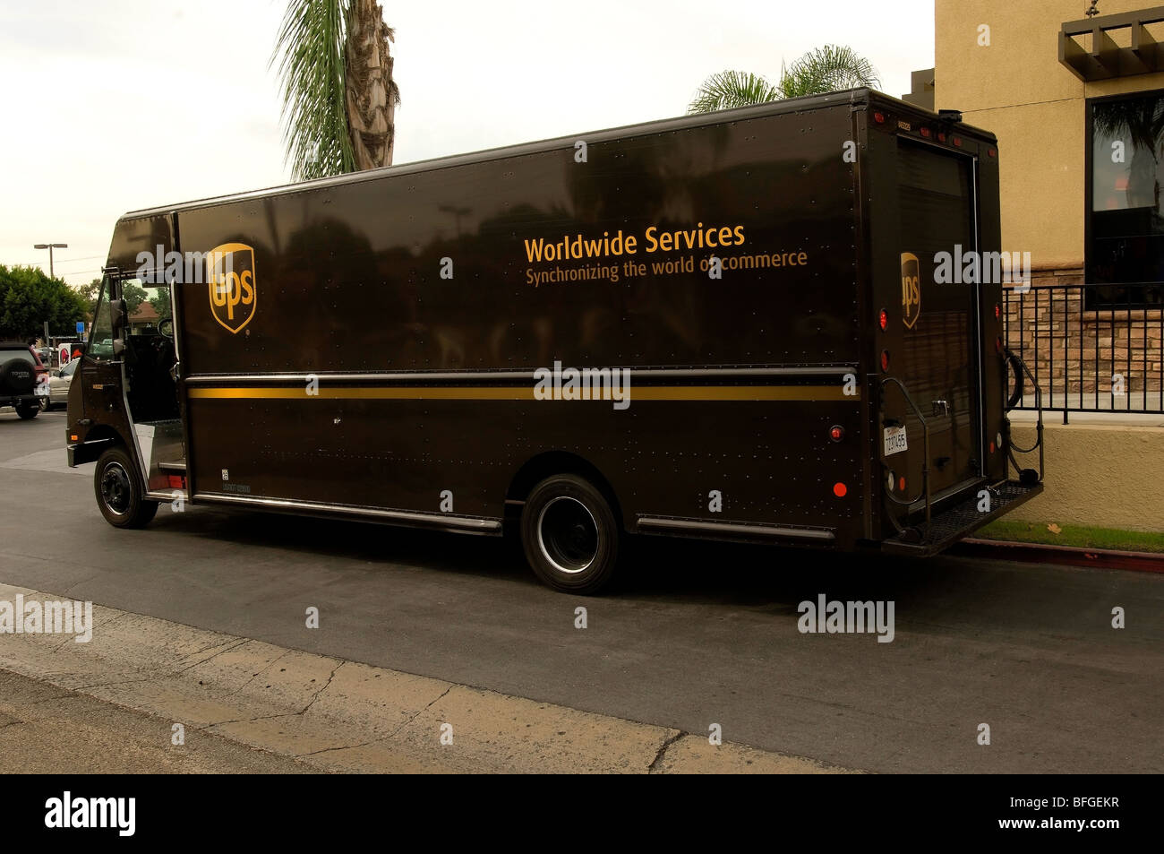 Brown UPS truck parked in front of a business making a rush delivery. Stock Photo