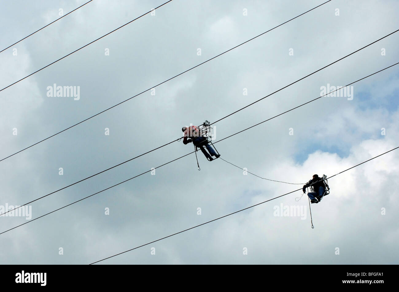 Power line workers doing dangerous work hanging from live electrical