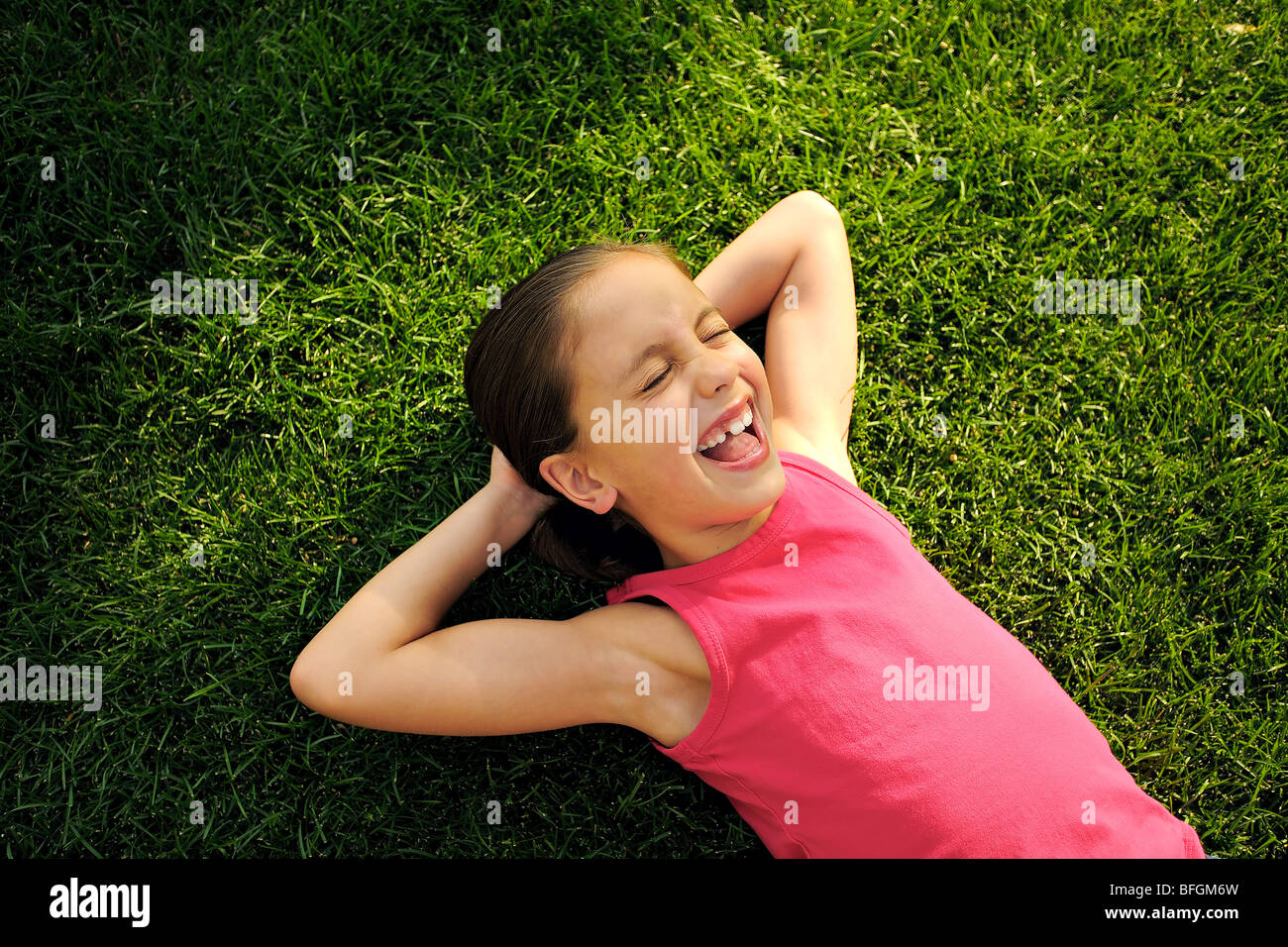 Young girl laying on lawn with hands behind head, Toronto, Ontario