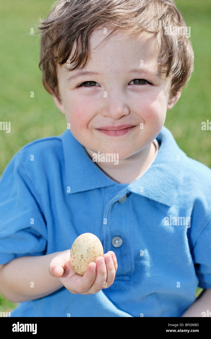 Young boy holding an egg in his hand, King City, Ontario Stock Photo