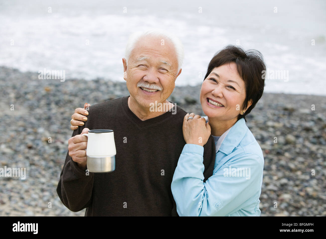 Senior couple at beach looking at camera Stock Photo