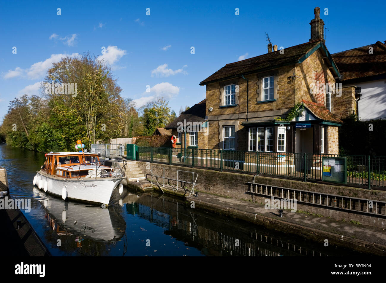A boat passing a traditional riverside lock keeper's cottage at