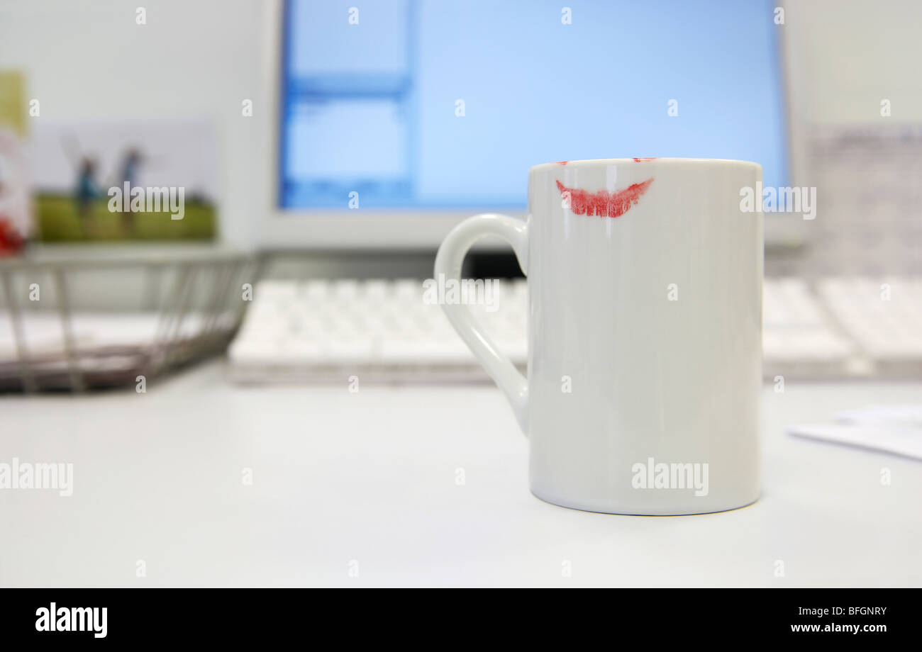 Lipstick Print on Coffee mug by computer on desk, close up Stock Photo