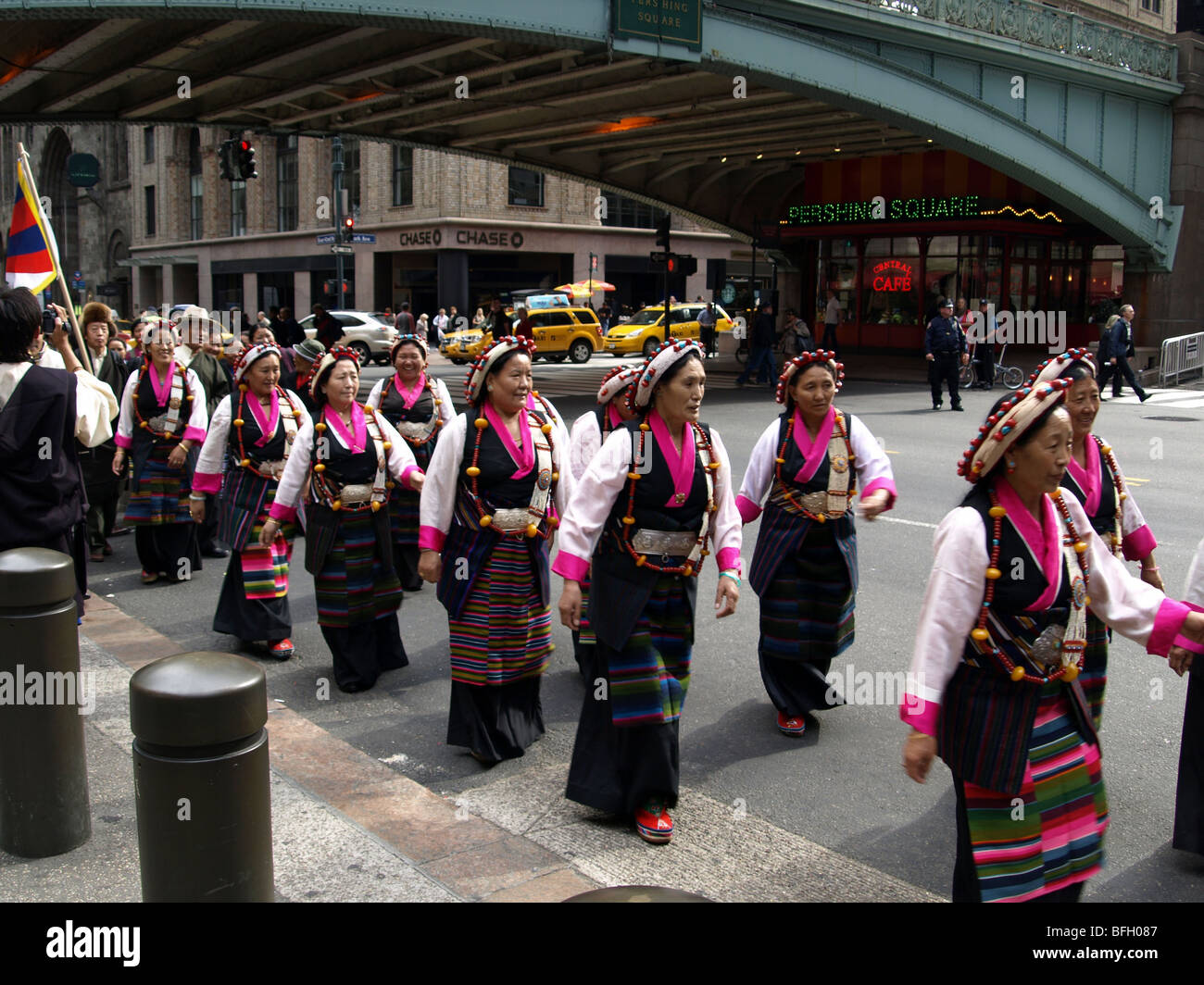 Tibetan parade in New York with smiling women in traditional costume showing a glimpse of their flag. Stock Photo