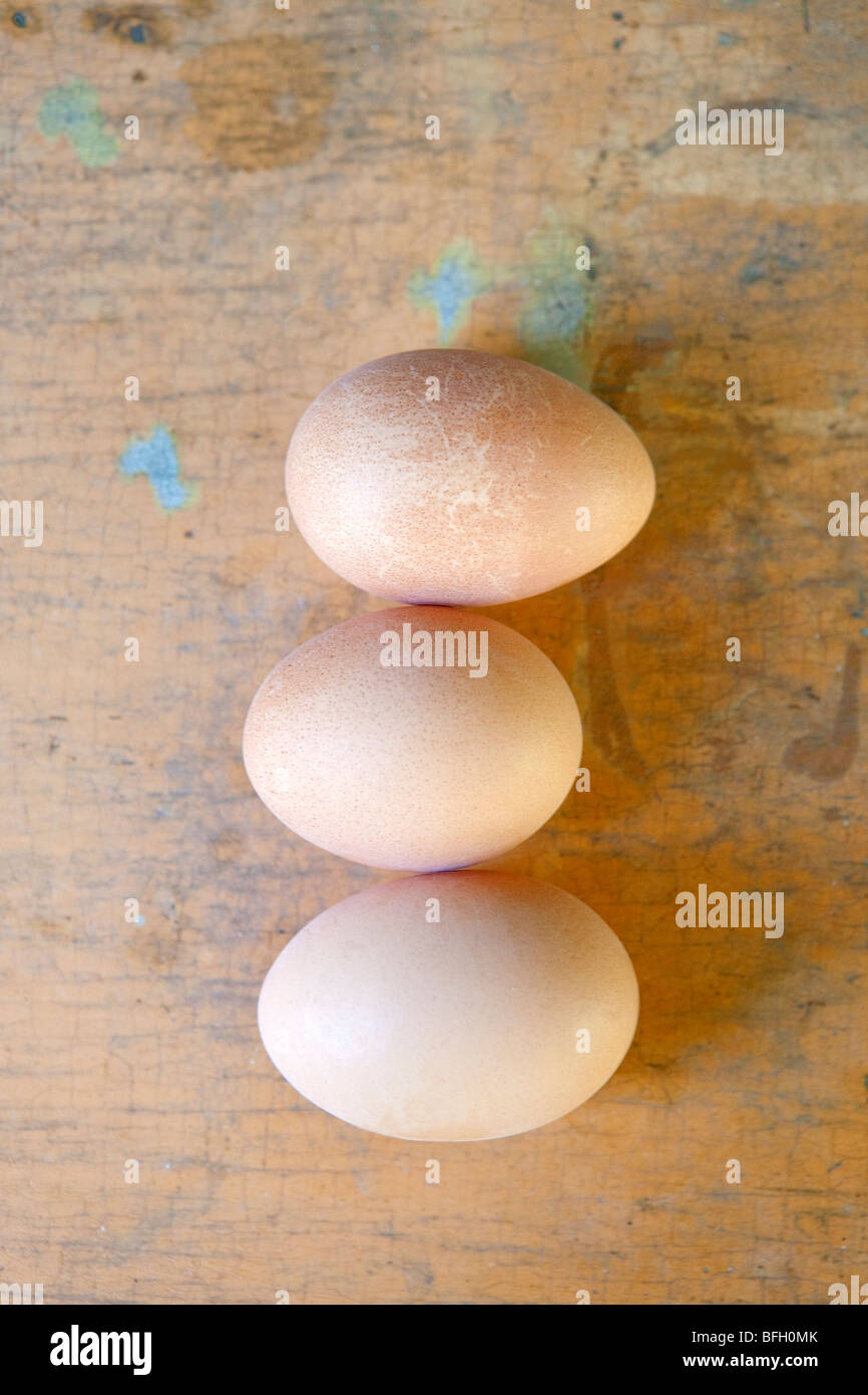 three brown hen eggs on rustic surface Stock Photo