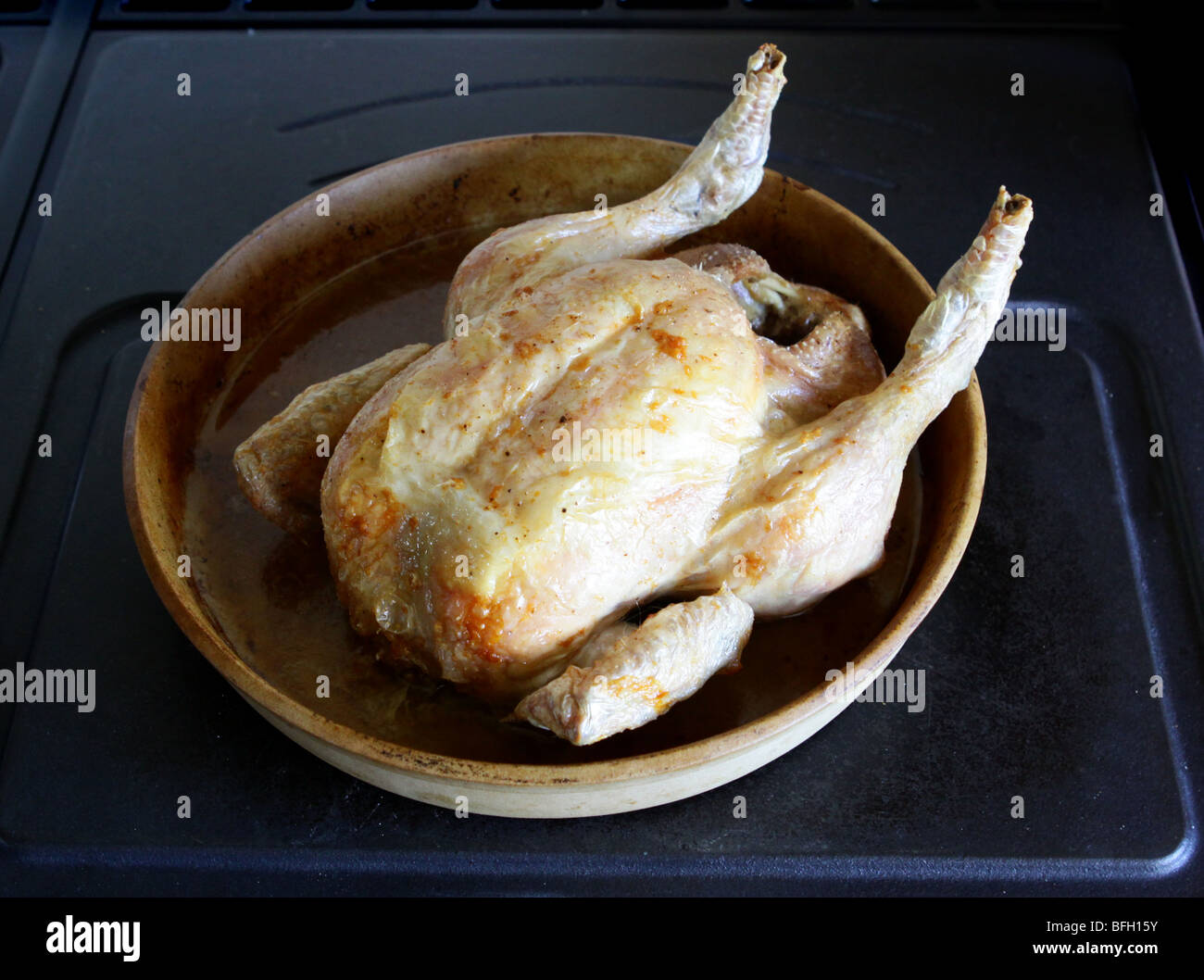Cooked ready to eat Roast Chicken in a terracotta pampered chef roasting dish Stock Photo