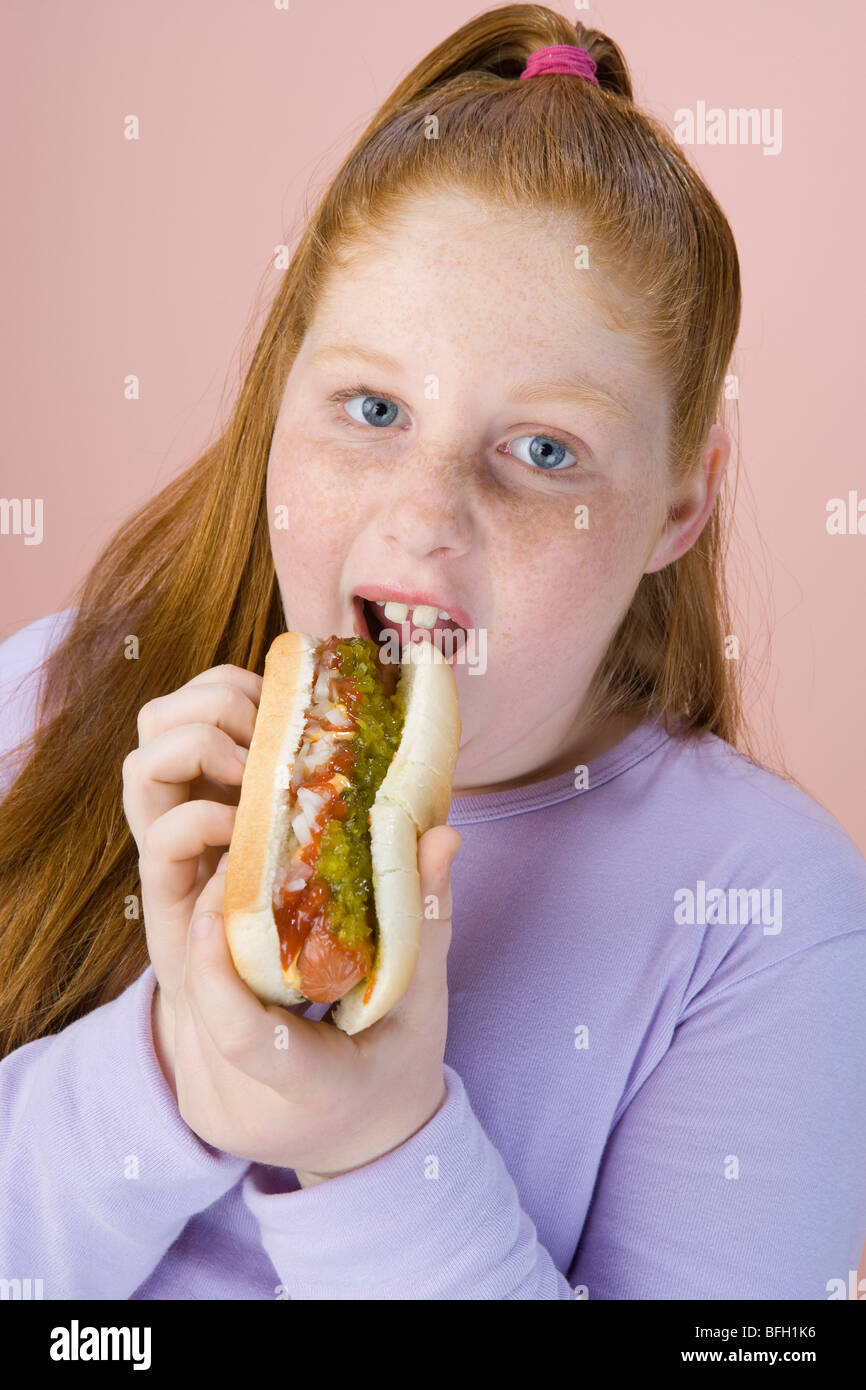Overweight girl eating hot dog, portrait Stock Photo
