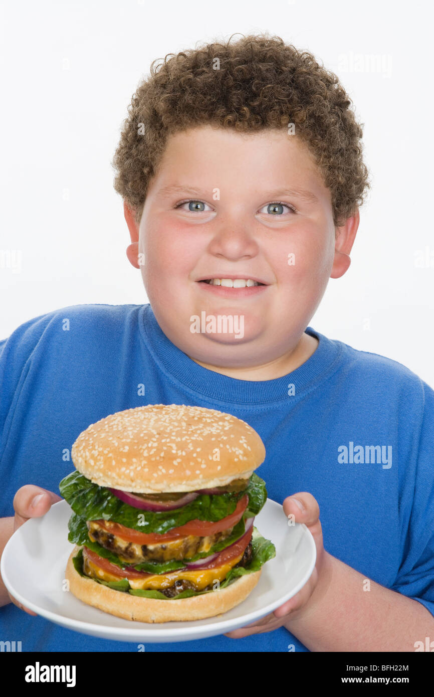 Overweight boy holding plate with big cheeseburger Stock Photo Alamy