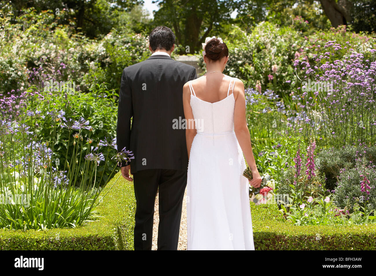 Bride and groom walking in garden, back view Stock Photo - Alamy
