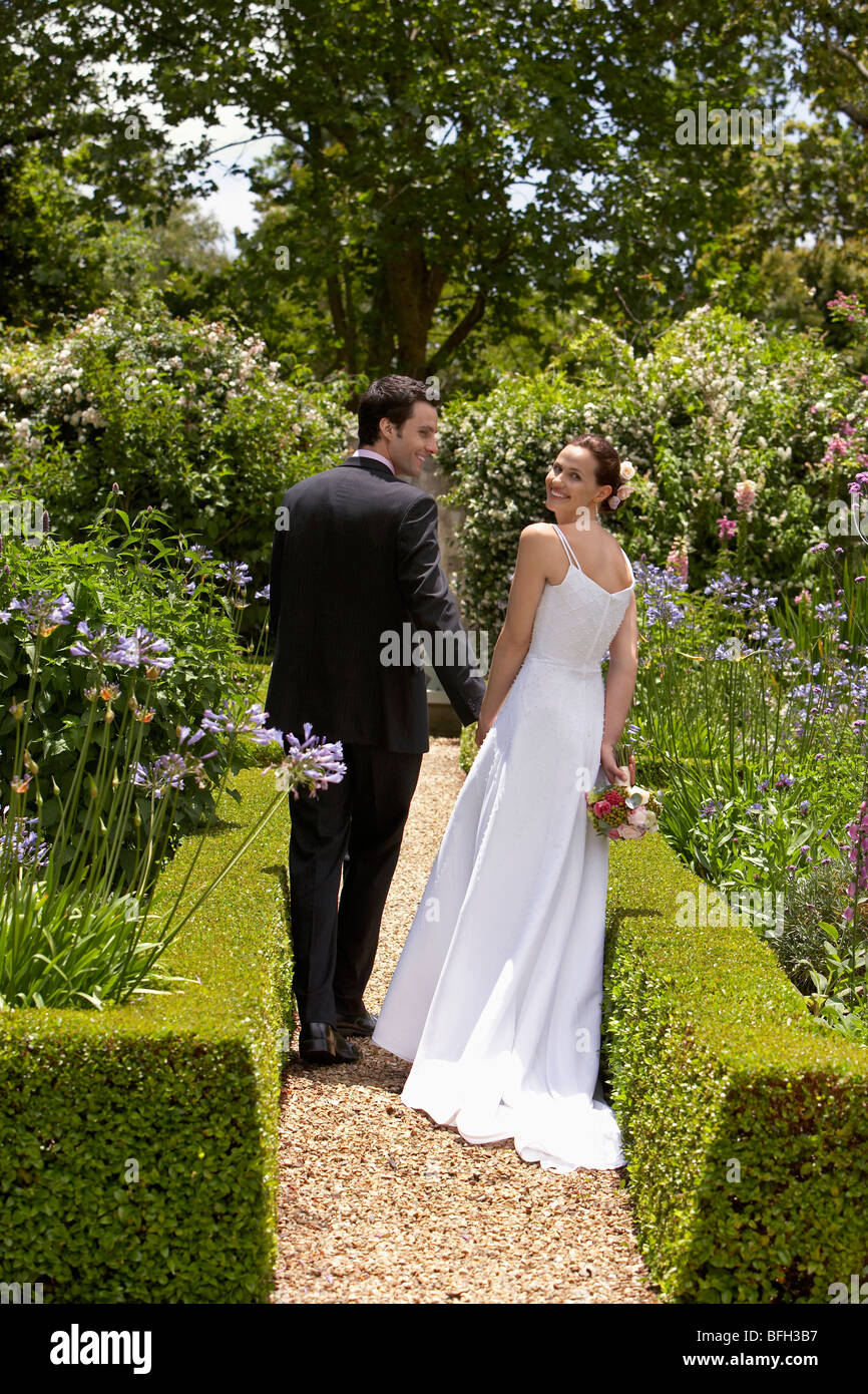 Bride and groom walking in garden, back view Stock Photo - Alamy
