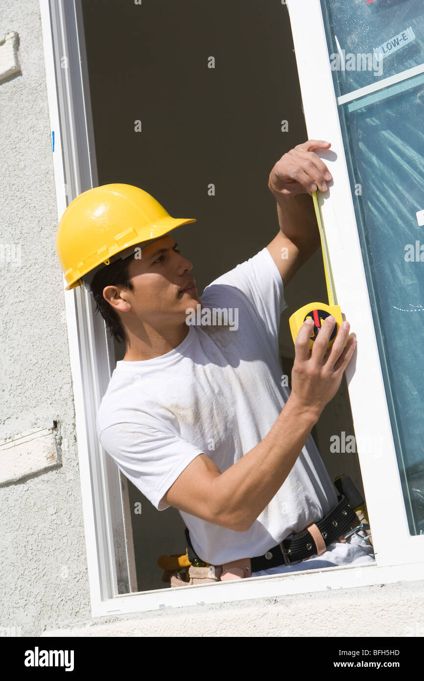 Construction Worker measuring window frame Stock Photo - Alamy
