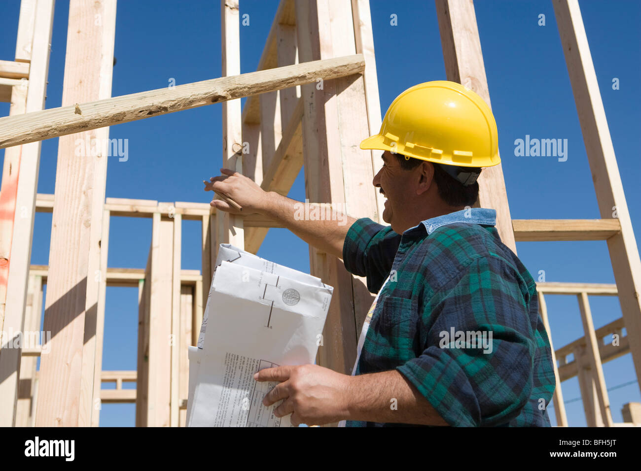 Construction worker holding blueprint, smiling Stock Photo - Alamy