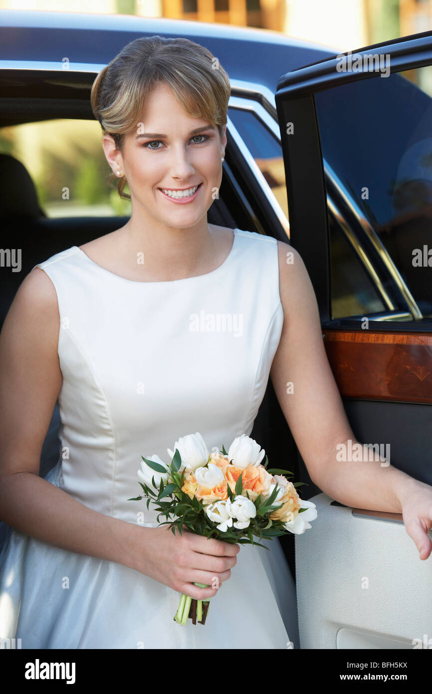 Young woman holding bouquet in open door of limousine, portrait Stock Photo