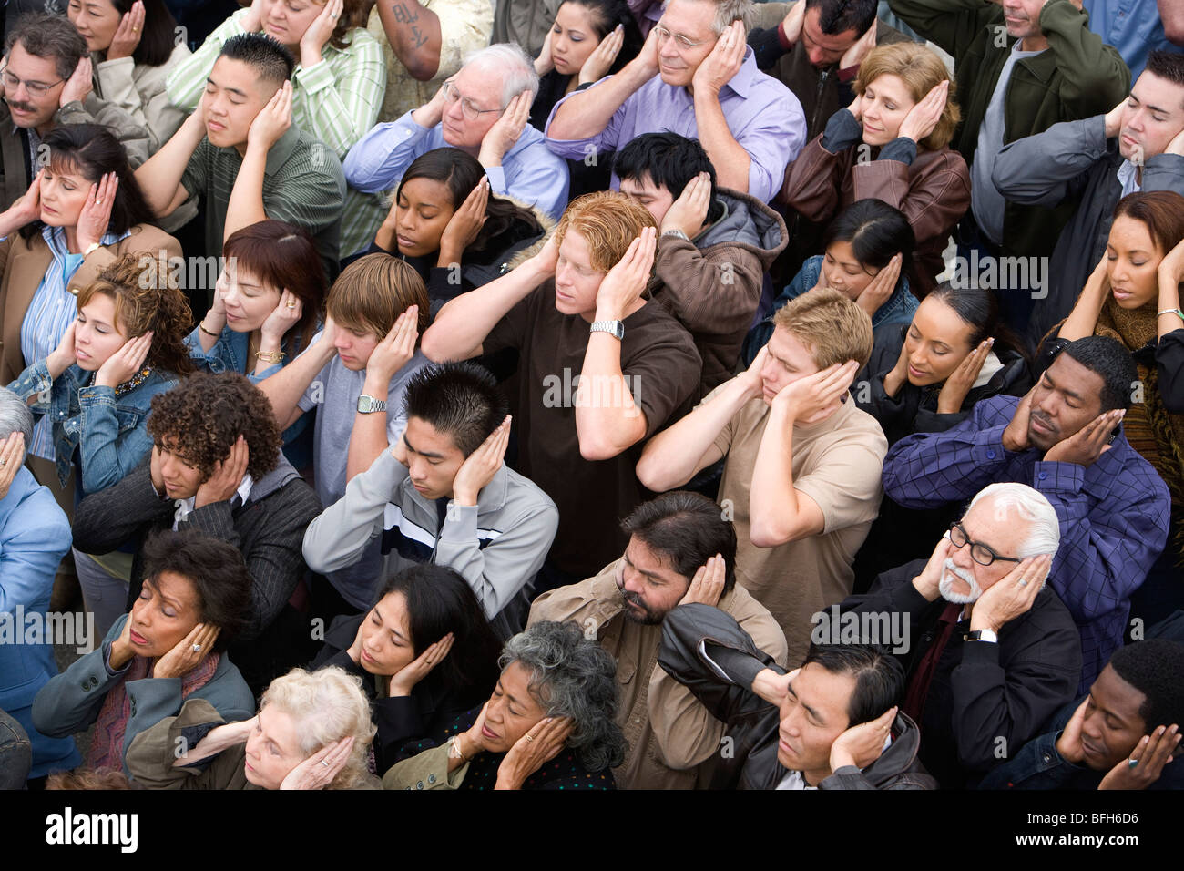 Crowd covering ears Stock Photo