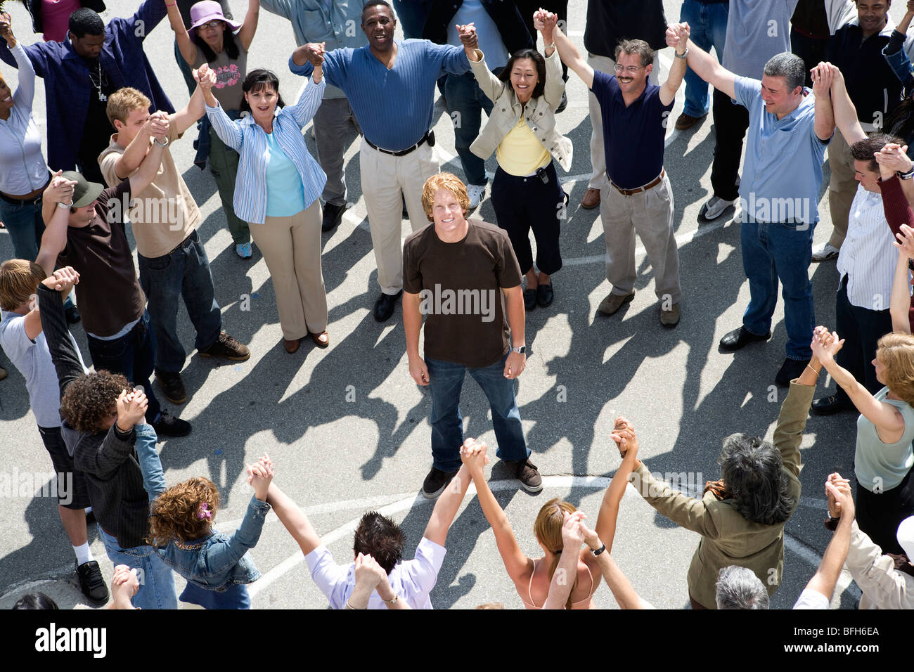 Crowd with arms raised surrounding young man Stock Photo