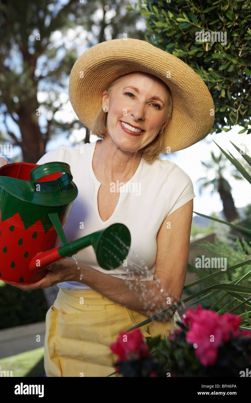 Woman watering flowers in garden Stock Photo - Alamy