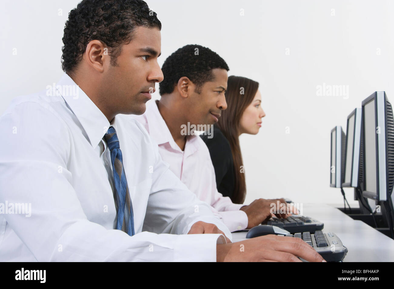 Three business people using computers in office Stock Photo - Alamy