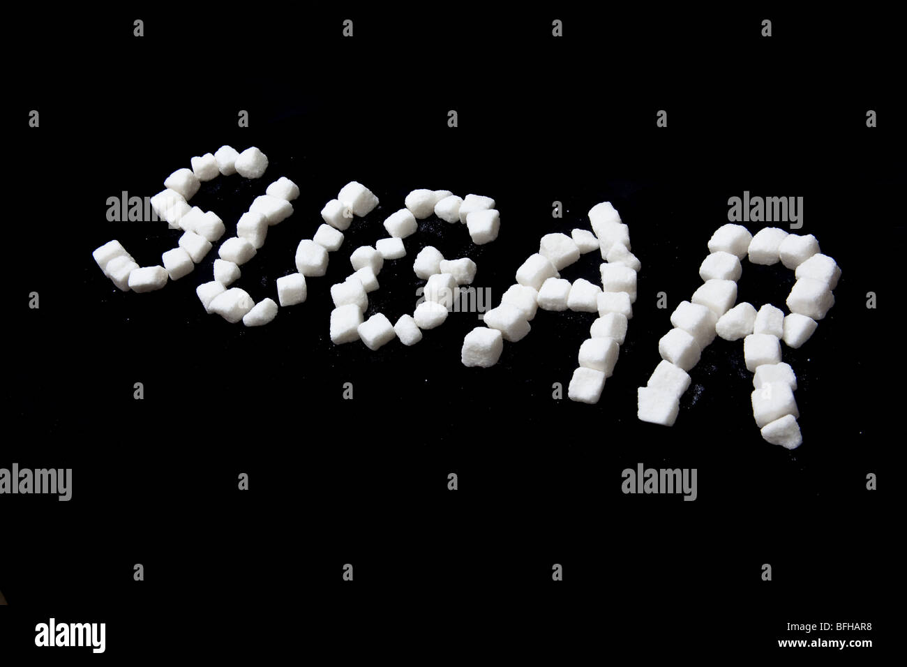 Sugar written in sugar lumps on a black studio background. Stock Photo