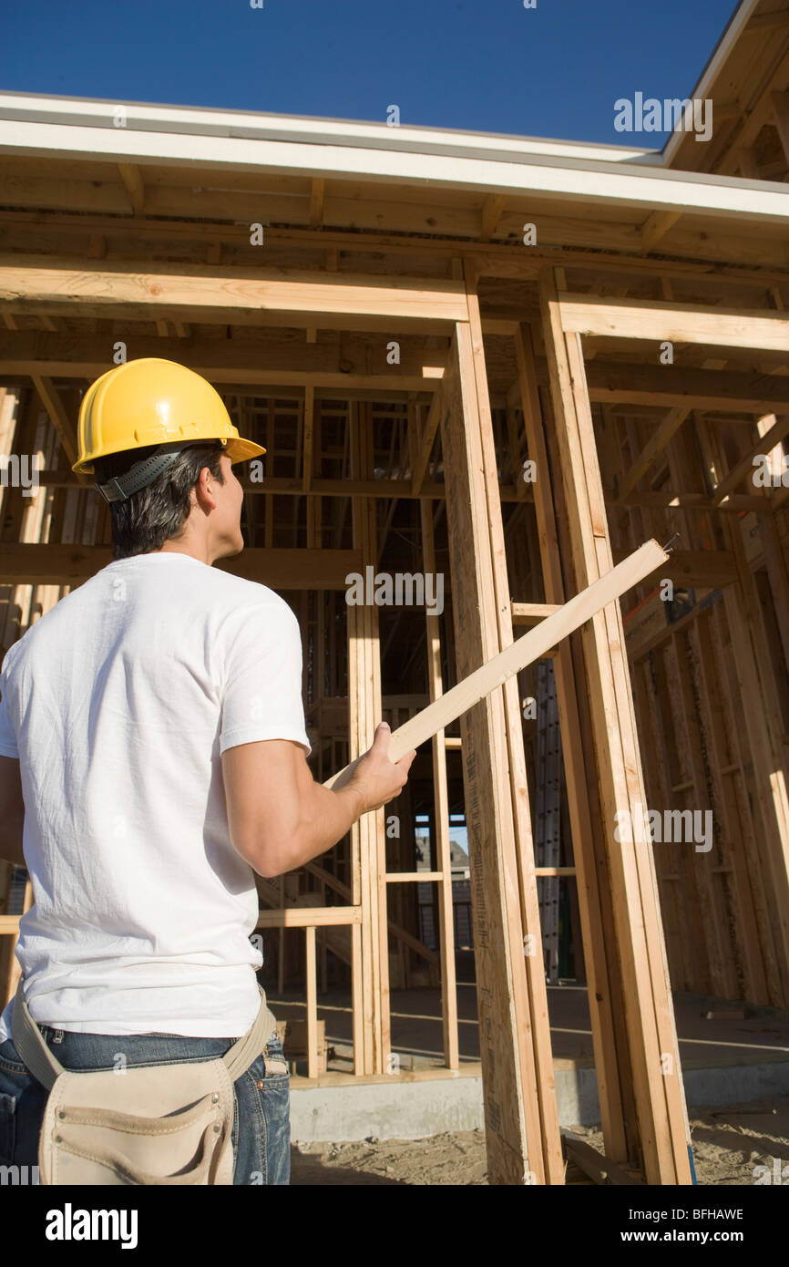 Construction worker carrying wooden beam Stock Photo