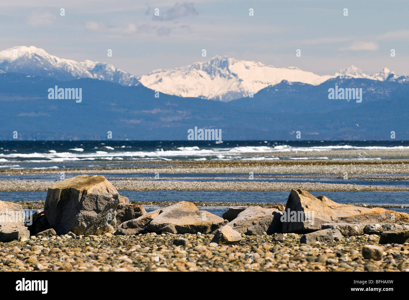 BC's Mainland Coast Mountains tower over the beach at Parksville, on Vancouver Island. Stock Photo