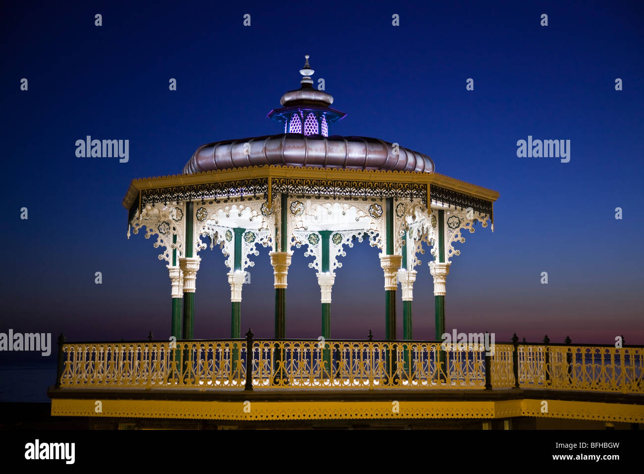 Grade 2 listed, restored Victorian bandstand featuring ornate ironwork, on Brighton and Hove seafront just after sunset. Stock Photo