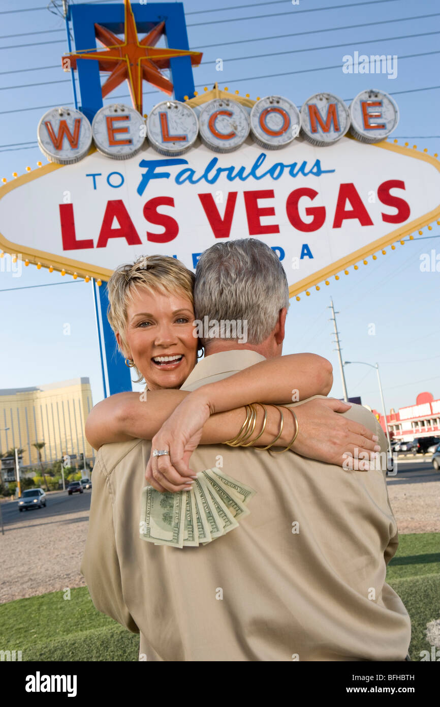 Middle-aged couple embracing in front of Welcome to Las Vegas sign Stock Photo