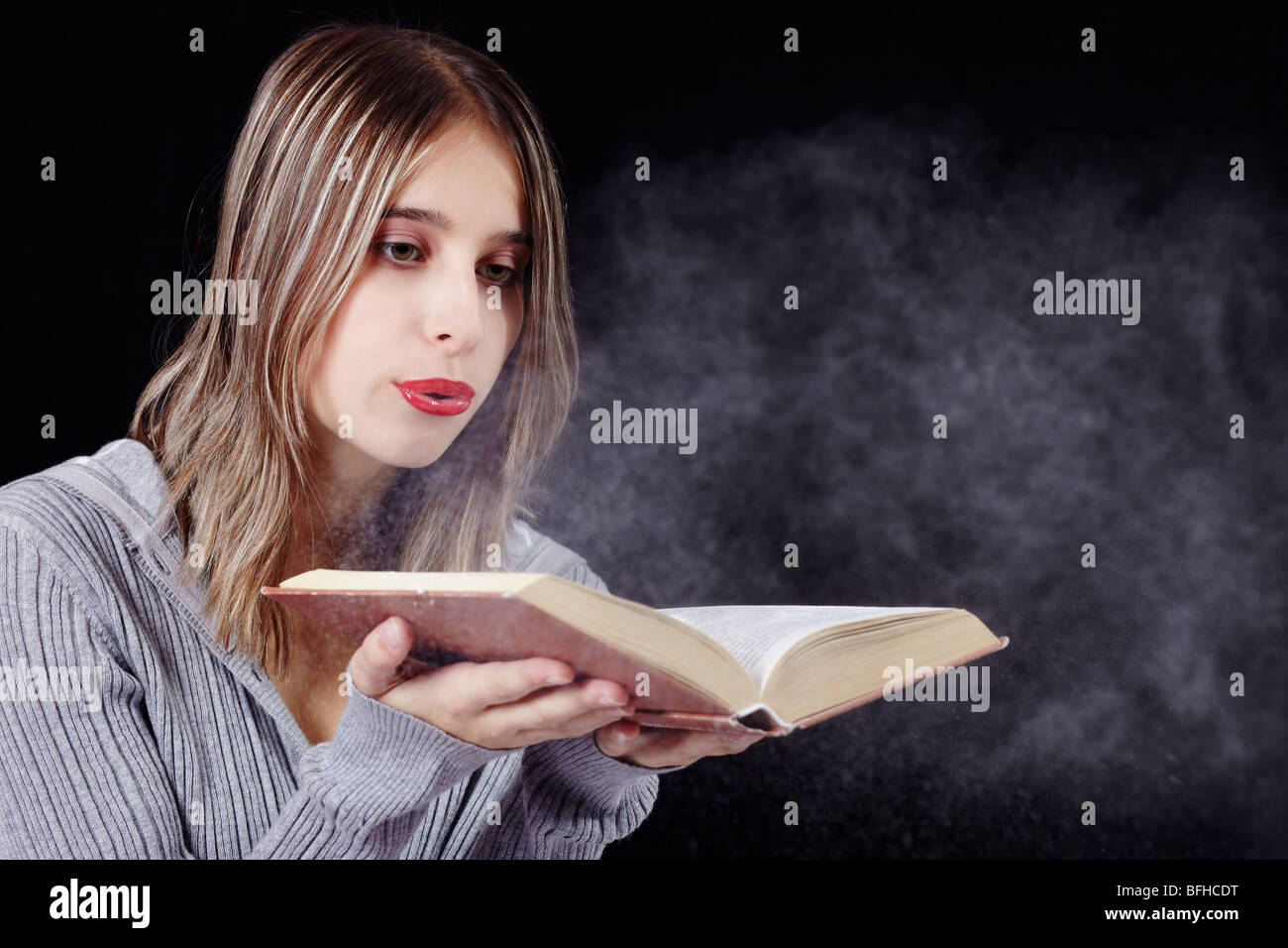 Young woman blowing dust from an old book Stock Photo Alamy