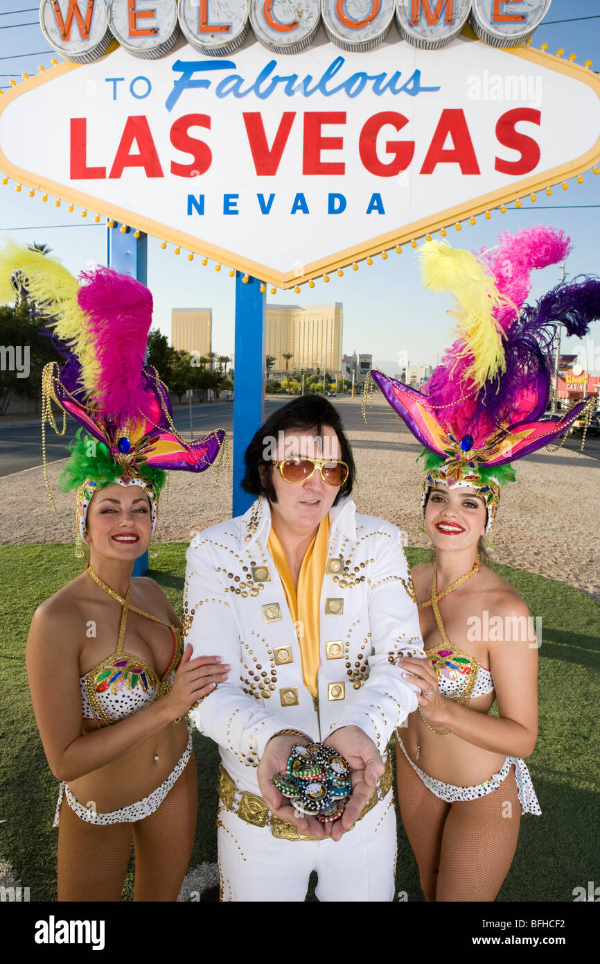 Female dancers and Elvis impersonator posing in front of Las Vegas welcome sign, Nevada, USA Stock Photo