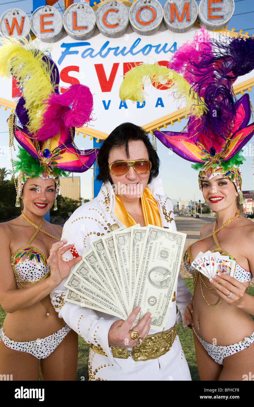 Female dancers and Elvis impersonator posing in front of Las Vegas welcome sign, Nevada, USA Stock Photo