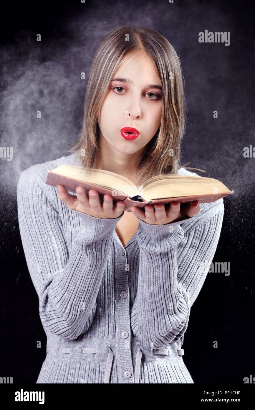 Young woman blowing dust from an old book Stock Photo Alamy