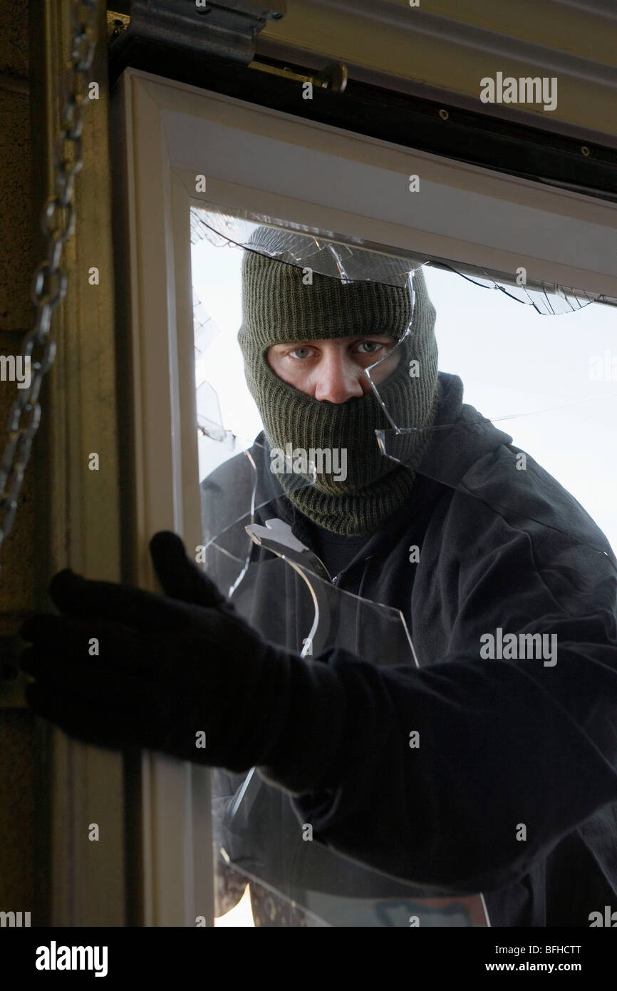 Masked thief braking in through window Stock Photo - Alamy