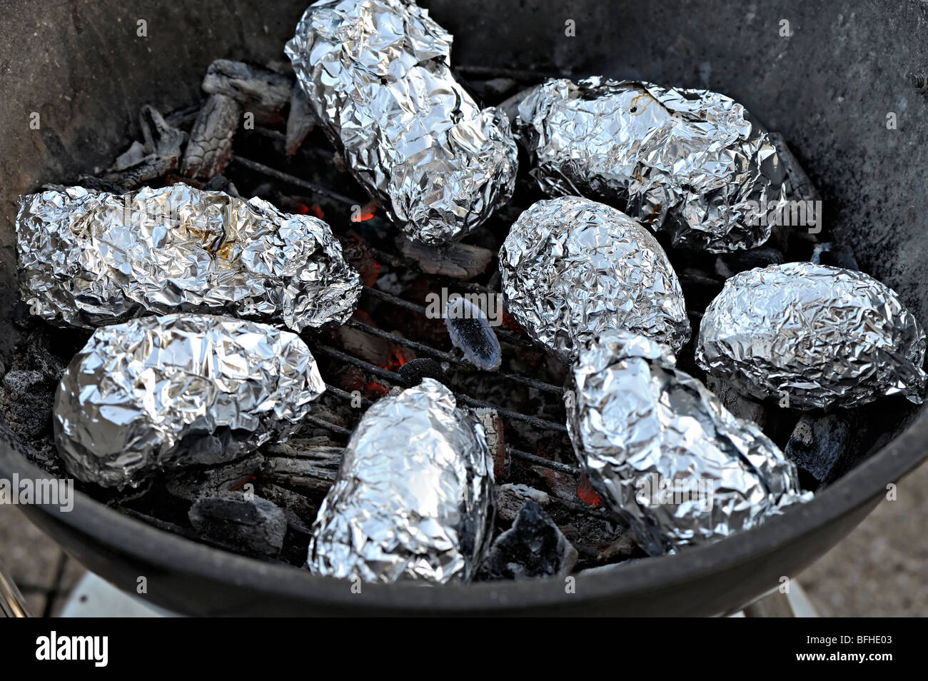 Potatoes wrapped in aluminum foil baking on the grill