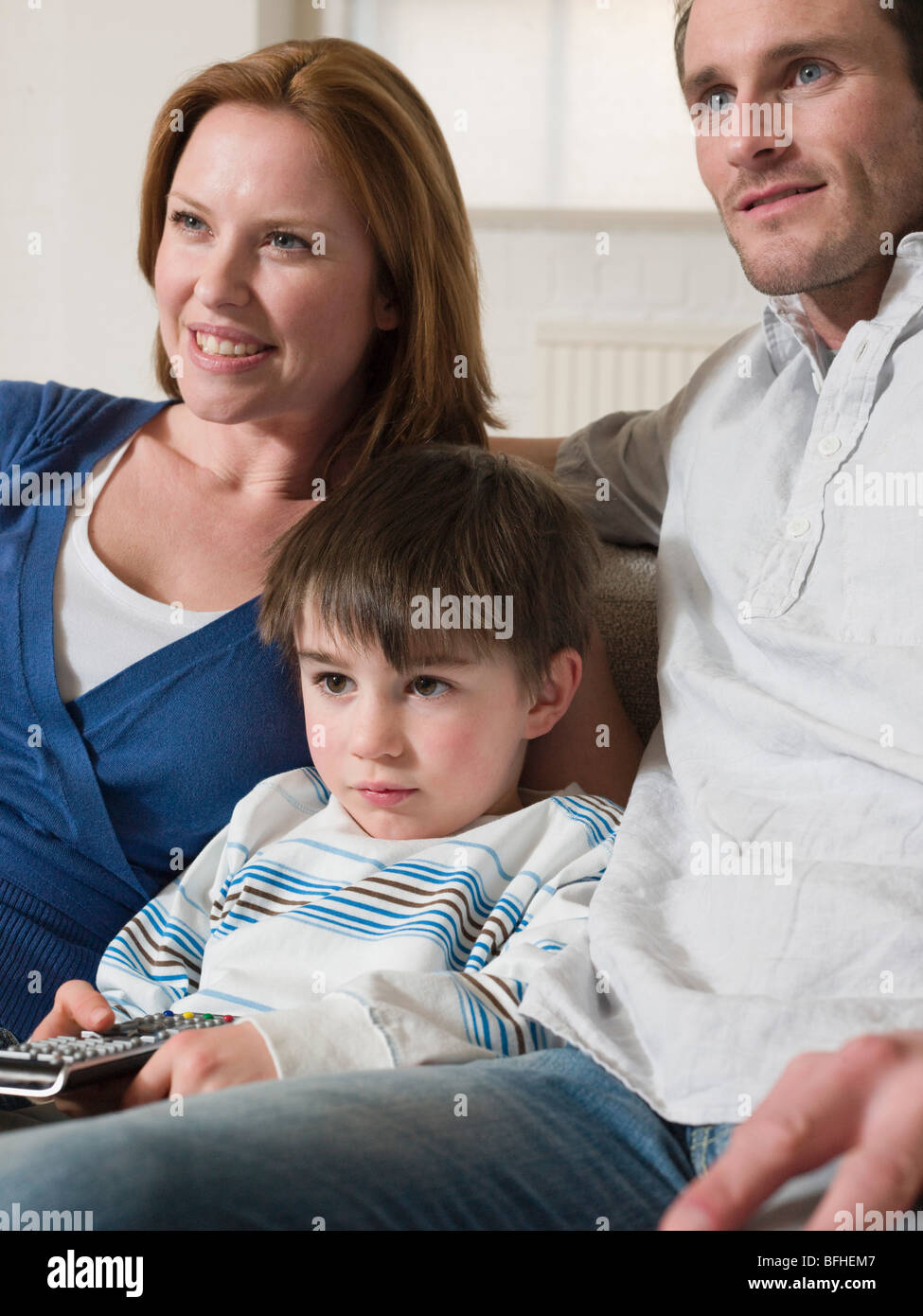 Boy Between Parents Watching Television Stock Photo