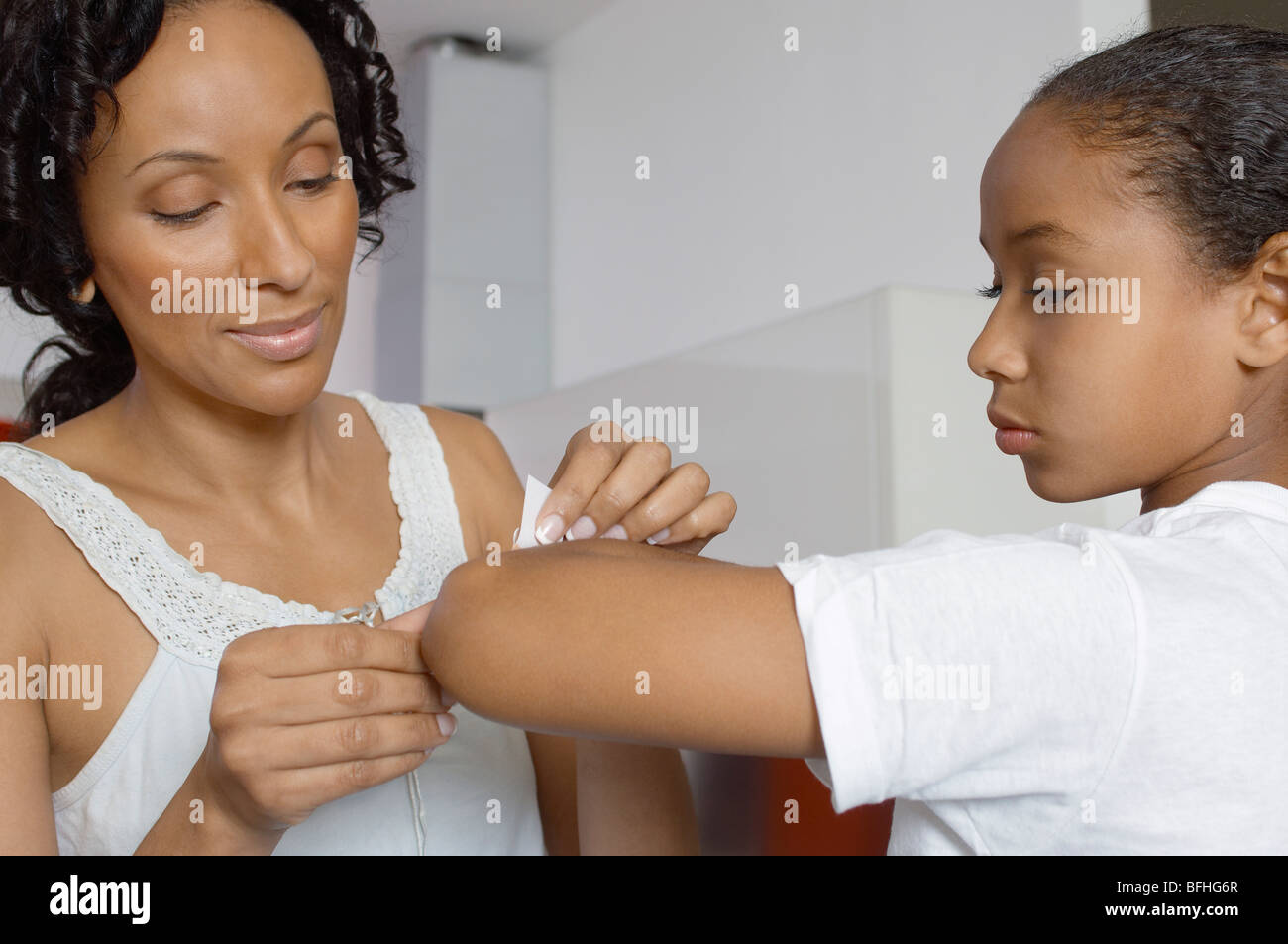 Mother applying bandaid to daughter (79) indoors Stock Photo Alamy