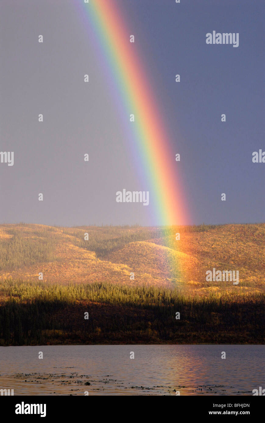 Rainbow on distant shoreline of alpine lake. Unnamed lake. Yukon