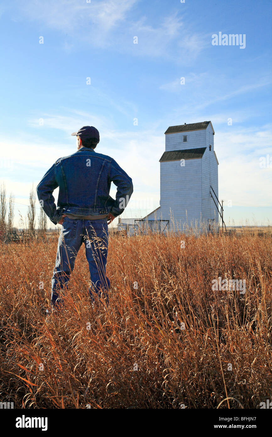 Farmer standing in field with grain elevator Stock Photo Alamy