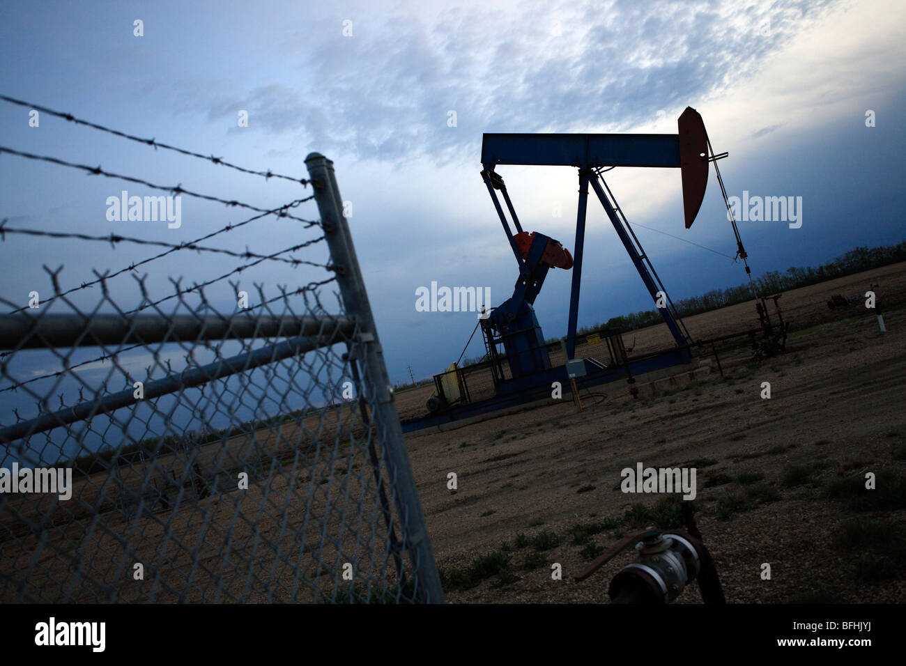 Oil pump jack in evening with fence in Alberta, Canada Stock Photo Alamy