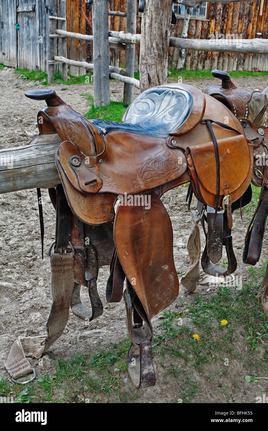 A riding saddle straddles a pst on ranch near Calgary Alberta Canada. Stock Photo