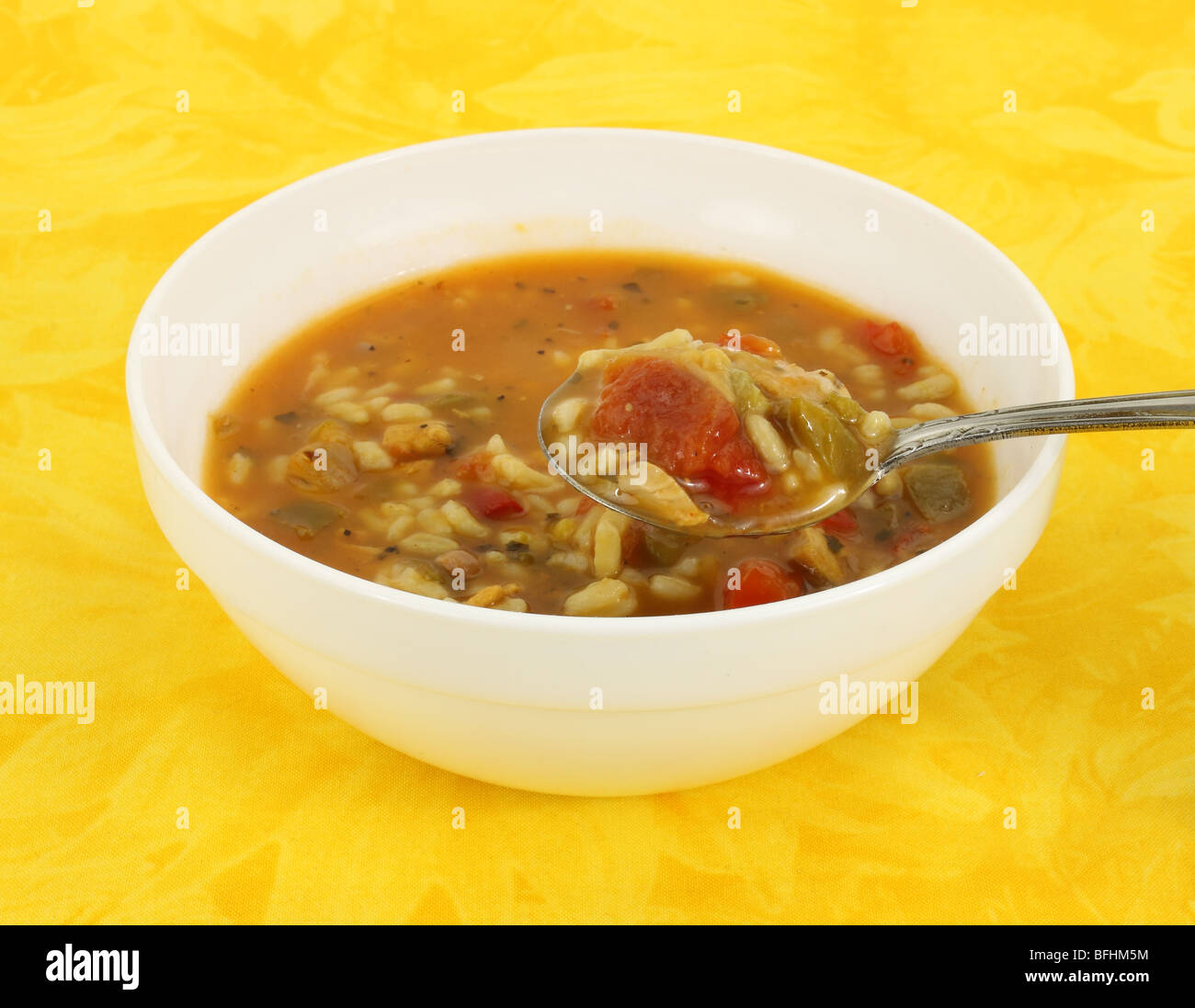 Spicy chicken soup in a white bowl with spoon Stock Photo