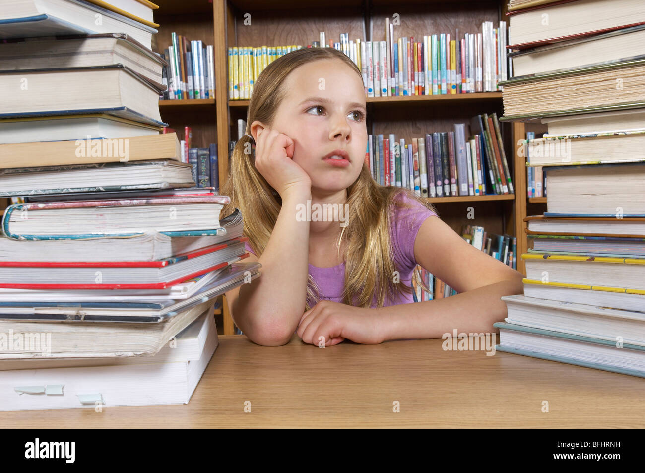 School girl sitting at desk with books in library Stock Photo - Alamy