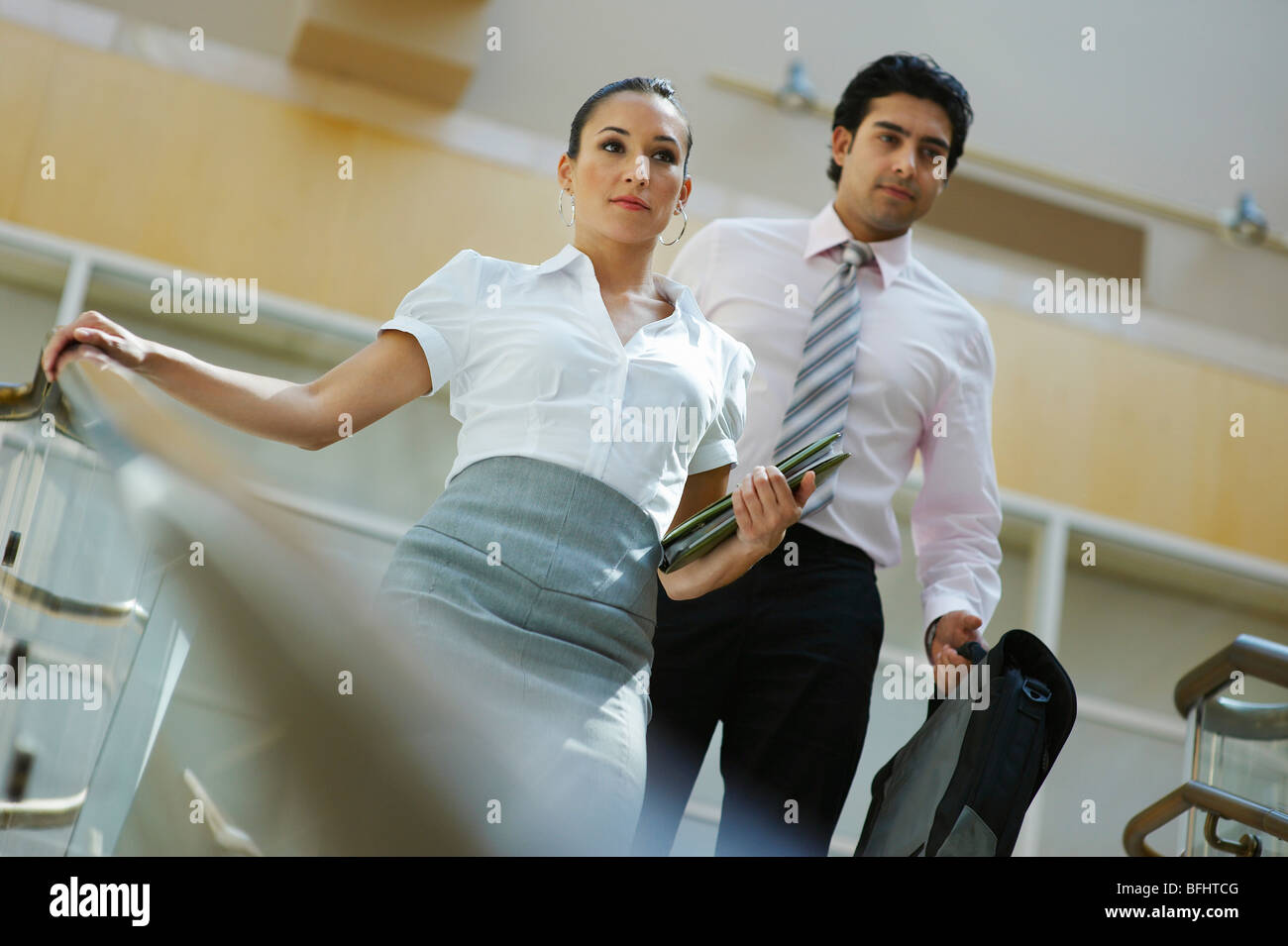Young business woman and business man walking down stairs Stock Photo ...