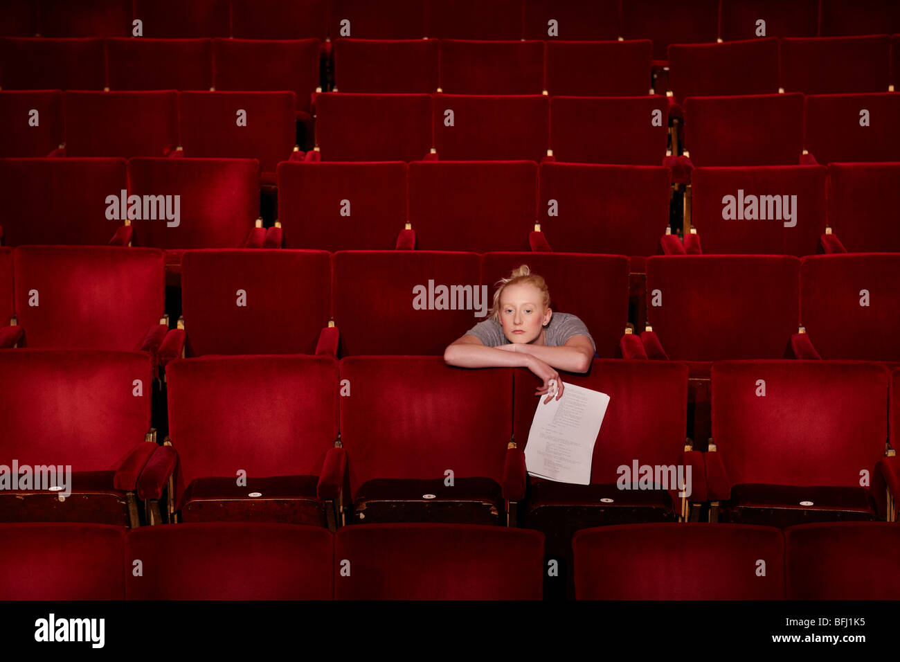 Young woman sitting in theatre stalls Stock Photo