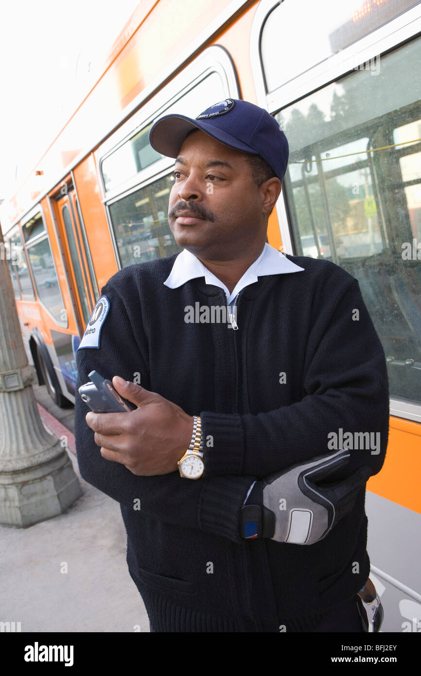 Bus driver holding mobile phone by bus Stock Photo - Alamy