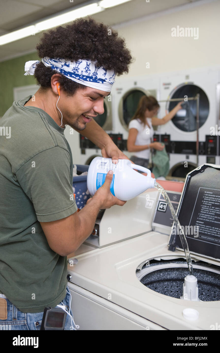 Young man washing clothes at launderette Stock Photo