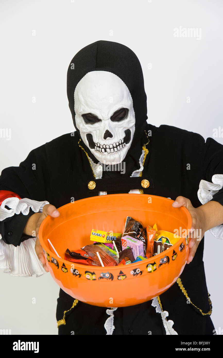 Portrait of boy (79) wearing skeleton mask, holding candy bowl Stock