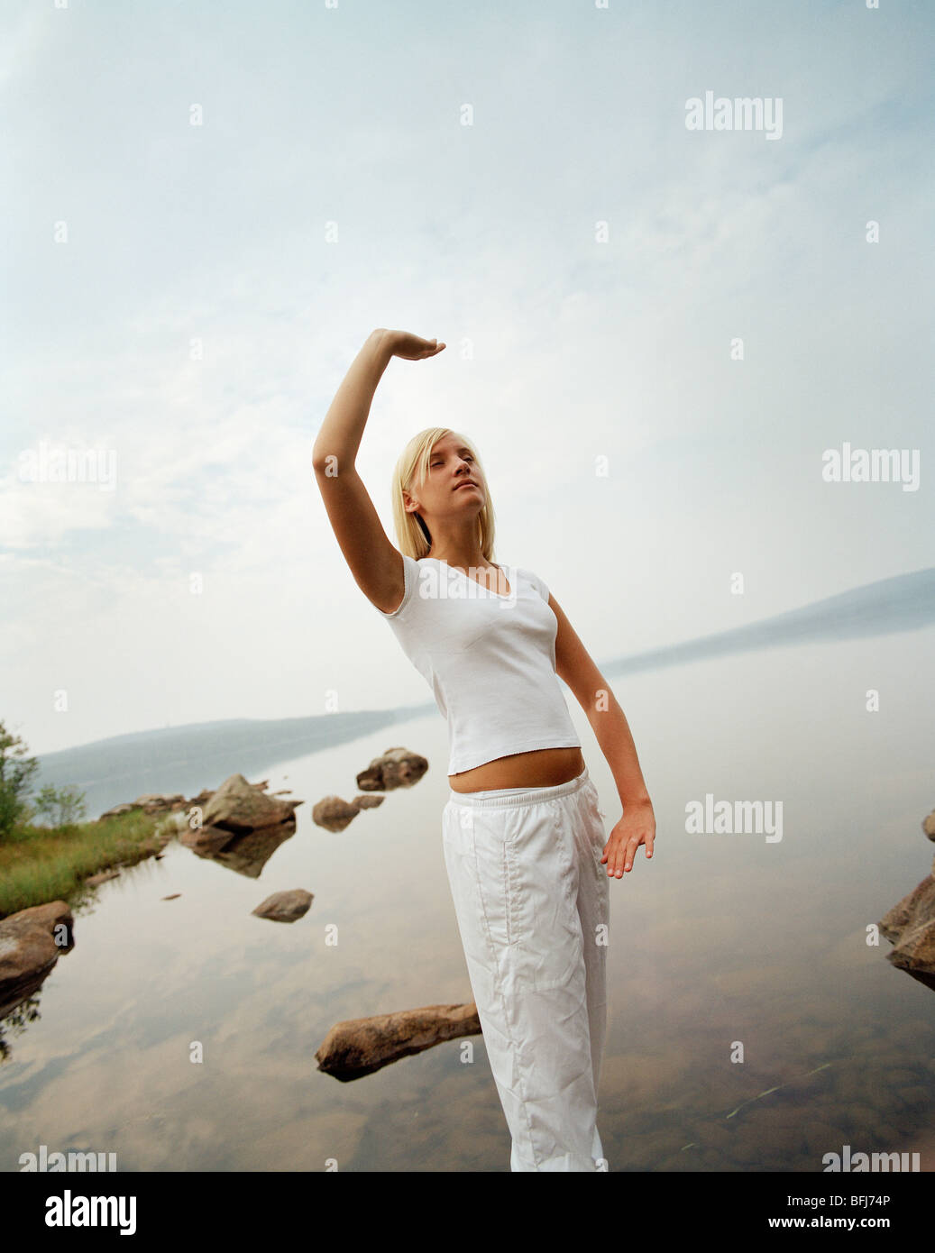 Young woman practising yoga by a lake, Sweden Stock Photo Alamy