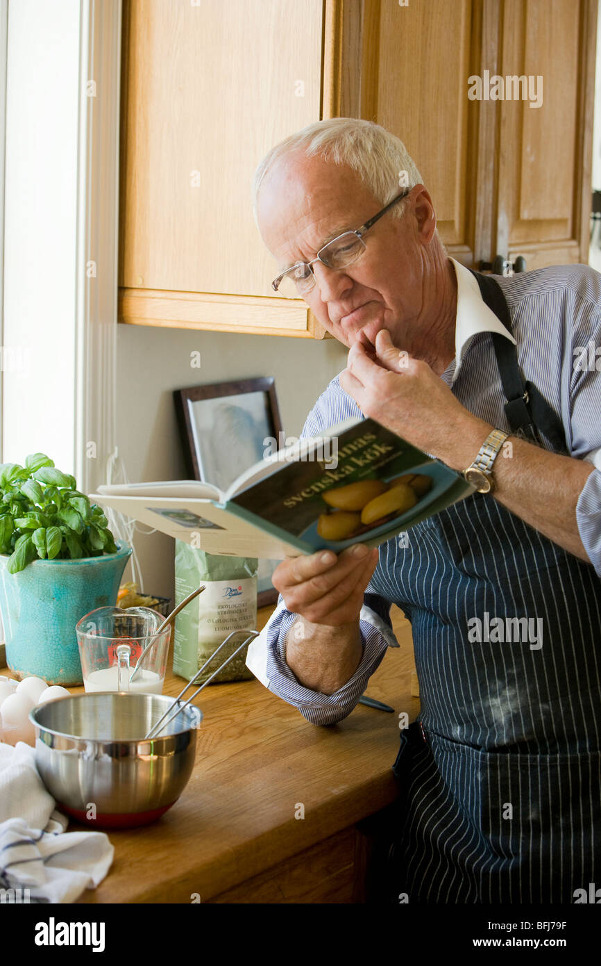 Senior man about to cook reading a cookbook, Sweden. Stock Photo