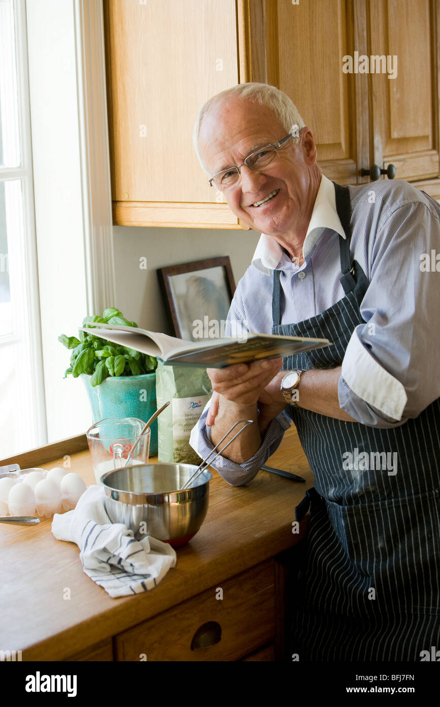 Senior man about to cook reading a cookbook, Sweden. Stock Photo