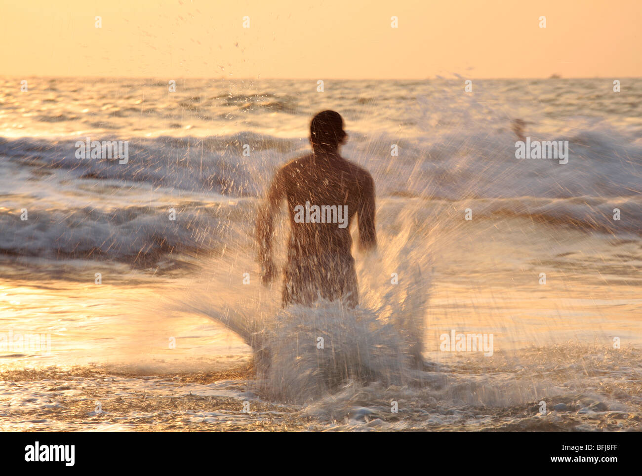 man crashing into the waves at goa Stock Photo